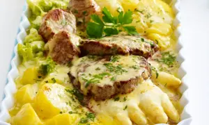 Herzhafte Spargelgerichte mit Fleisch: zarte Medaillons auf Kartoffeln und Spargel, überbacken mit Käse und garniert mit Petersilie.