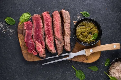 Perfekt gegrilltes Porterhouse Steak, in Scheiben geschnitten, mit Pesto und Kräutersalz.