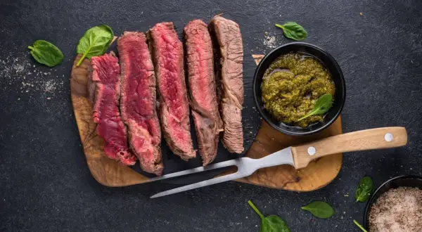 Perfekt gegrilltes Porterhouse Steak, in Scheiben geschnitten, mit Pesto und Kräutersalz.