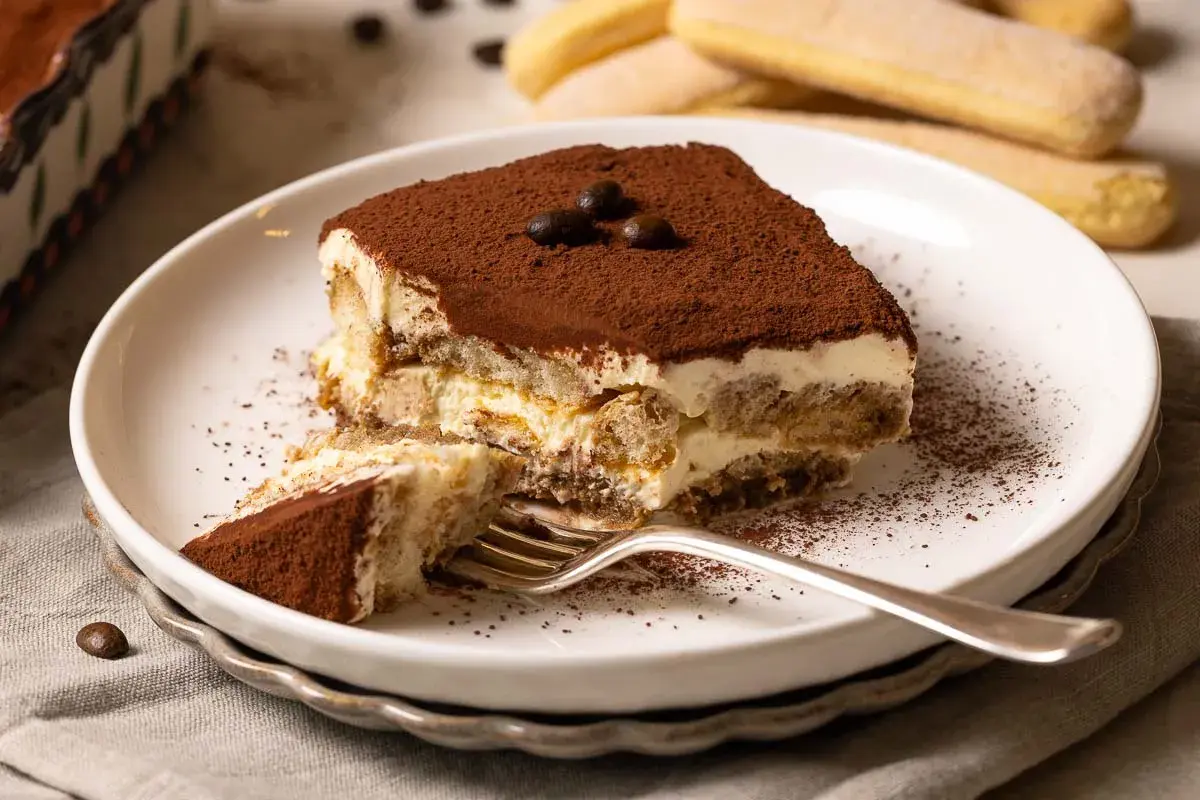 Ein Stück Tiramisu, perfekt für ein Tiramisu Rezept. Mit Löffelbiskuits, Creme und Kakaopulver bestäubt.