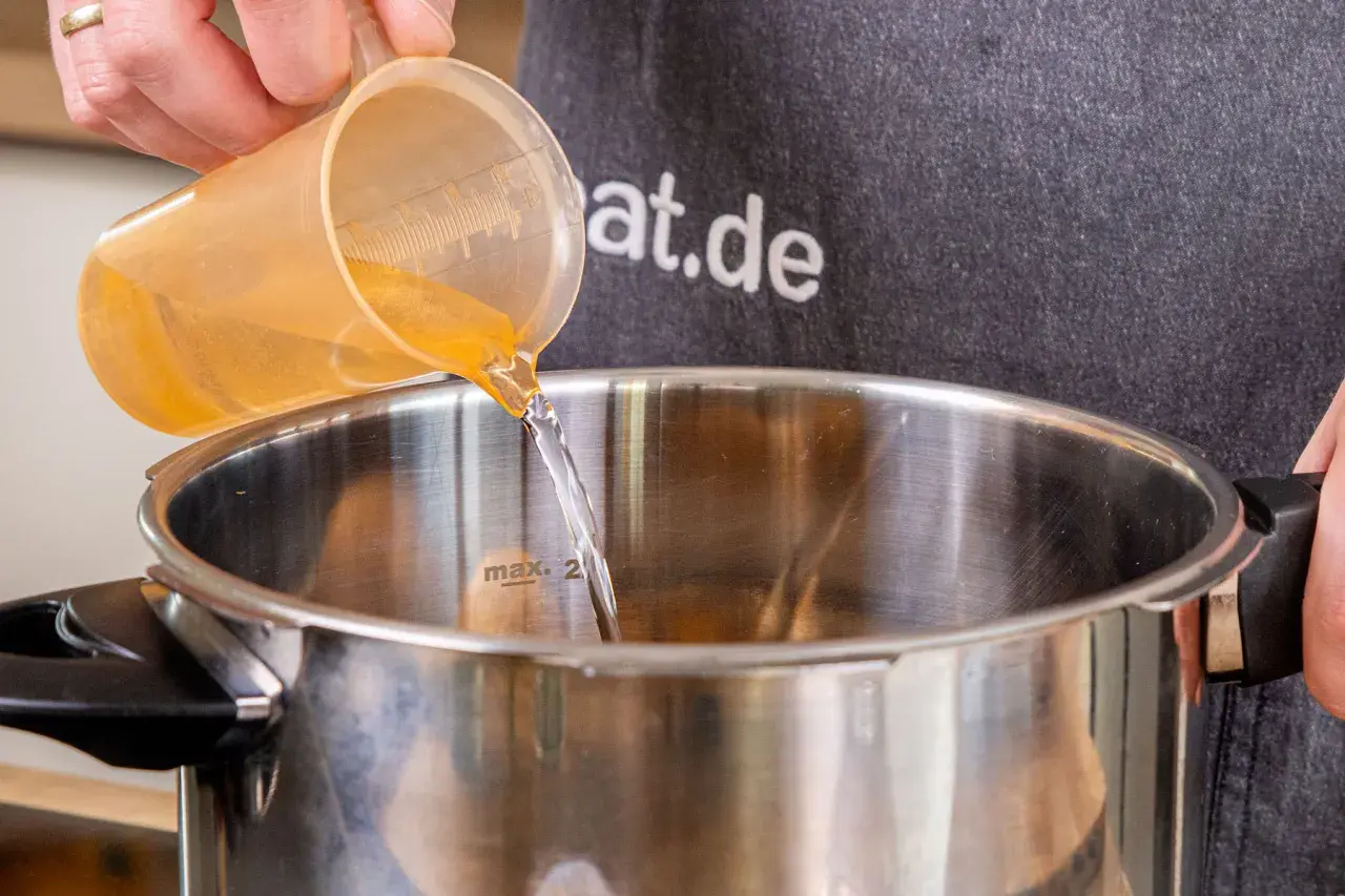 Flüssigkeit wird in einen Schnellkochtopf gegossen, bereit für die Zubereitung von Kartoffeln.