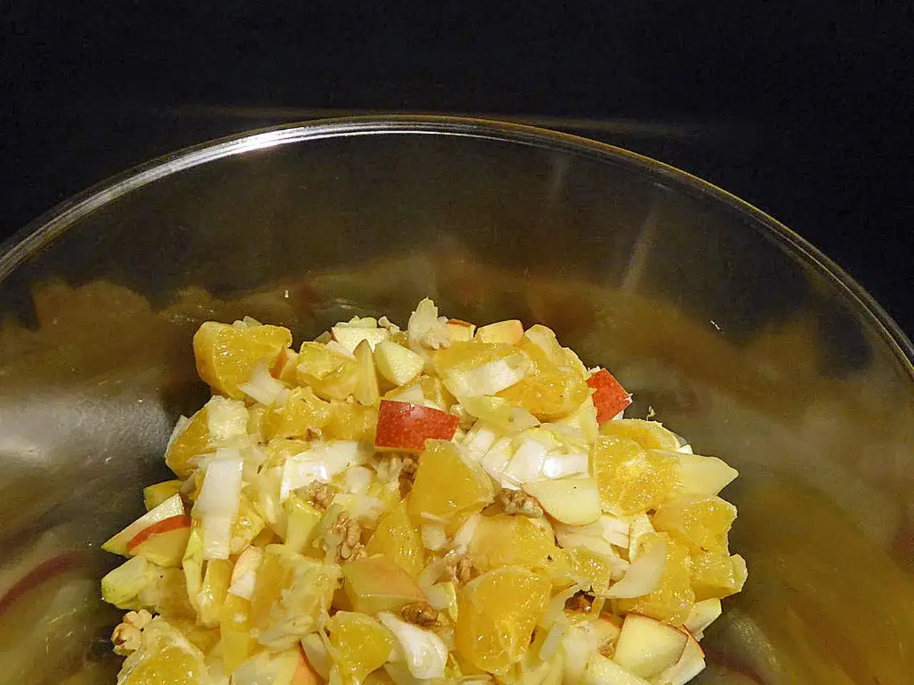 Ein erfrischender chicoree salat mit Orangenst&uuml;cken, &Auml;pfeln und Waln&uuml;ssen in einer Glassch&uuml;ssel.