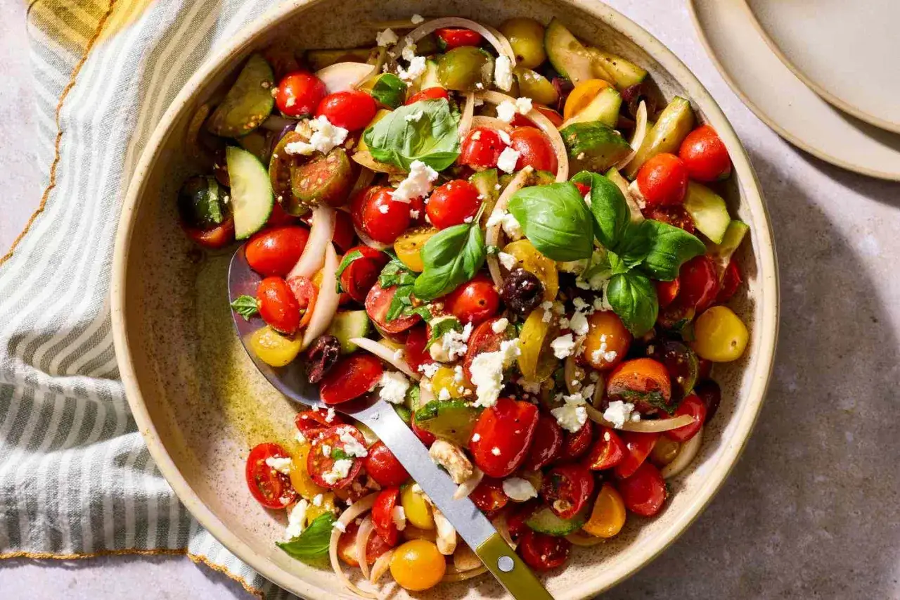Frischer tomatensalat mit feta, Gurken, Zwiebeln und Basilikum in einer Schüssel.