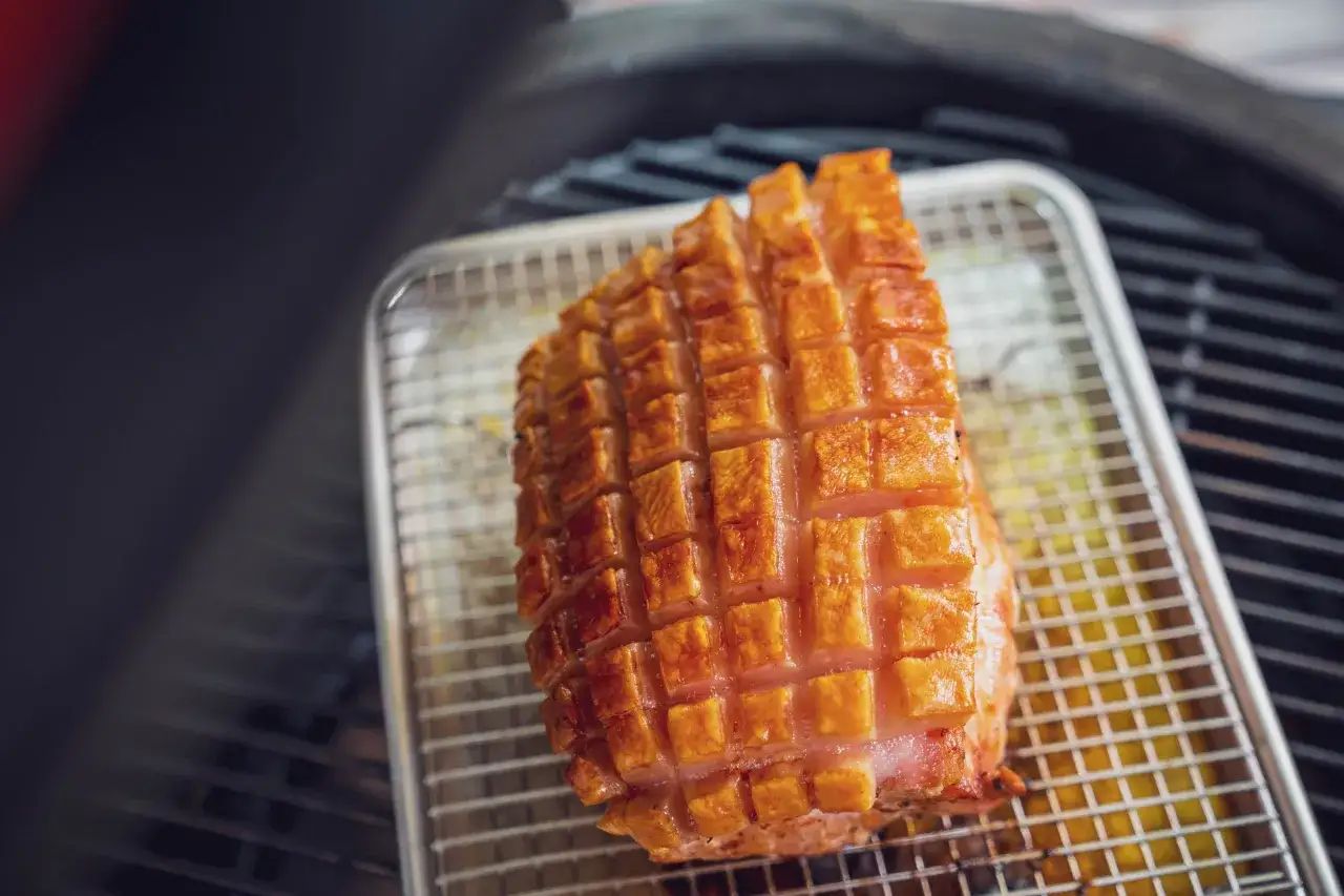 Ein knusprig gegrillter Schweinebauch auf einem Rost, bereit zum Genie&szlig;en. Die Schwarte ist perfekt karamellisiert.