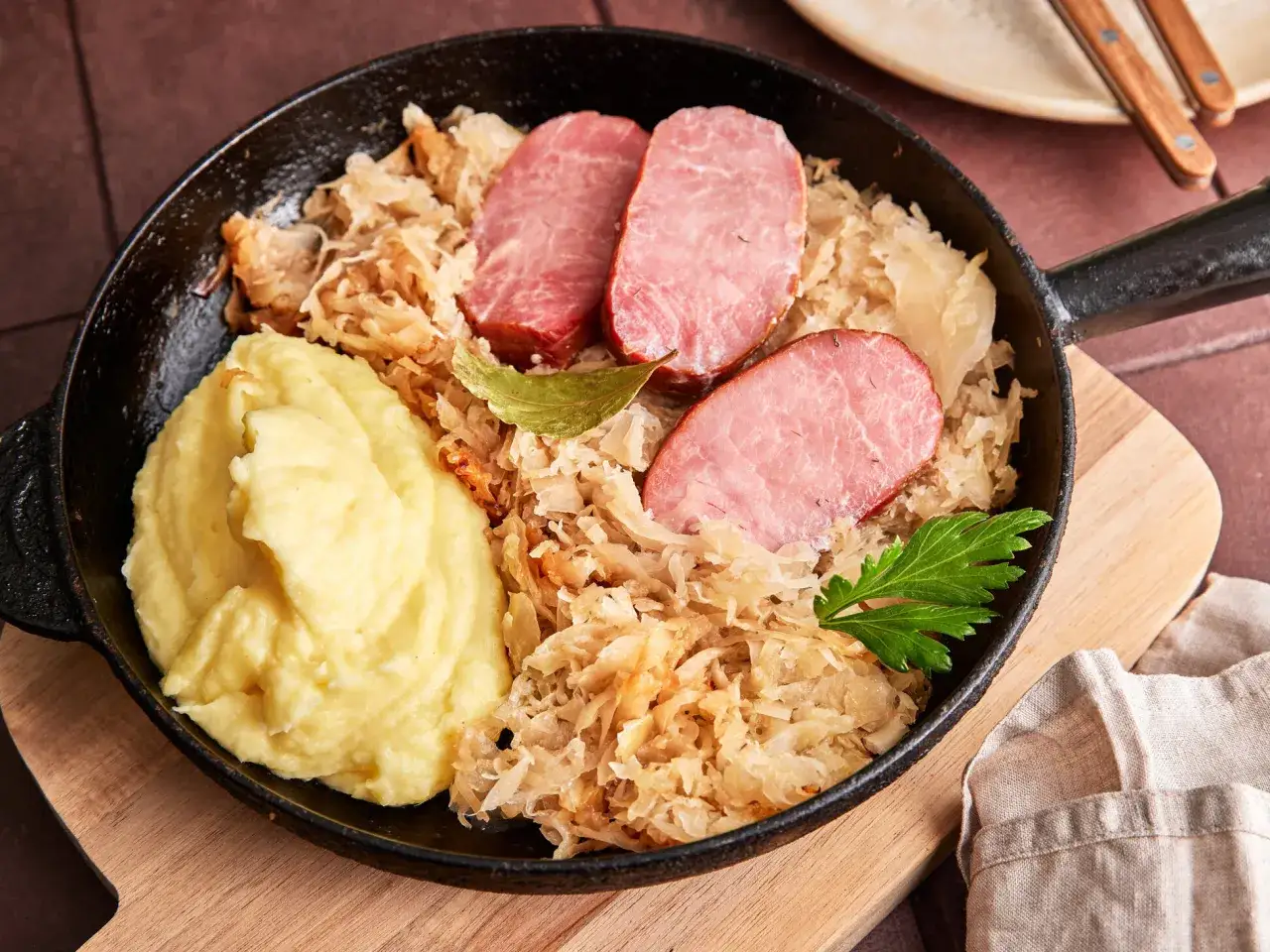 Kassler in Sauerkraut mitkochen wie lange? Herzhaftes Gericht mit Kartoffelpüree, Kassler und Sauerkraut in einer Pfanne.