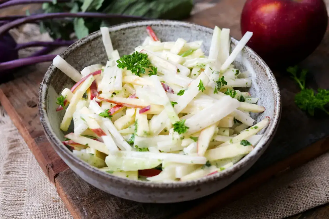 Ein cremiger Kohlrabi-Salat mit Apfelst&uuml;cken und frischer Petersilie, garniert mit einem Apfel.