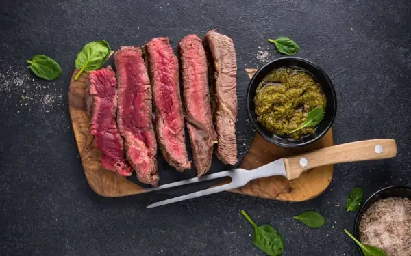 Perfekt gegrilltes Porterhouse Steak, in Scheiben geschnitten, mit Pesto und Kräutersalz.