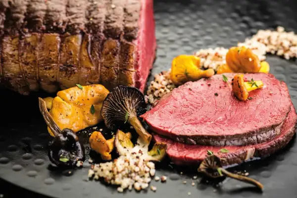 Zarter Rinderbraten im Ofen, perfekt geschnitten, serviert mit Pilzen und Quinoa. Ein Festmahl!
